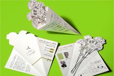 an origami brochure with flowers on it sitting on a green surface