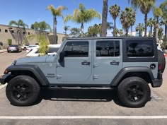 a gray jeep parked in a parking lot next to palm trees on a sunny day