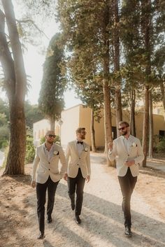 three men in suits walking down a path