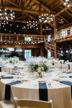 the tables are set with white and blue linens for an elegant wedding reception at the barn