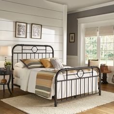 a metal bed frame in a bedroom with wood flooring and white painted walls, along with pictures on the wall