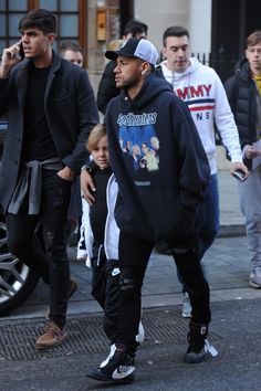 the man is walking down the street talking on his cell phone with two other men