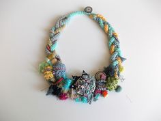 a multicolored necklace is displayed on a white surface with an object in the middle