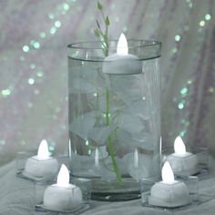 some white candles are in a glass vase