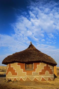 a hut in the middle of nowhere with blue sky and white clouds above it on a sunny day