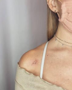 a woman's neck with a small bird tattoo on her left shoulder and chest