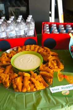 a table topped with lots of cheetos covered in sauce next to water bottles