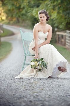 a woman in a wedding dress sitting on a blue chair with her hand on her knee