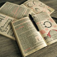 an open book sitting on top of a wooden table next to a pen and glasses