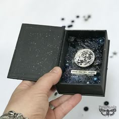 a hand holding an open box with a coin in it