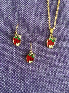 (11,671) Mini Strawberry Necklace or Earrings  Made from gold alloy enamel and glass,  1/2" x 3/8" A tiny strawberry with a white heart and a crystal  Earrings on gold tone ear wires Necklace on 18" gold tone chain Cute Gold Enamel Jewelry, Cute Gold Jewelry With Charms, Adjustable Enamel Pierced Jewelry, Adjustable Pierced Enamel Jewelry, Adjustable Enamel Jewelry, Cute Gold Earrings For Mother's Day, Cute Gold Dangle Jewelry, Gold Enamel Drop Earrings, Dainty Enamel Nickel-free Jewelry