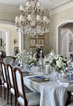 an elegant dining room with chandelier and blue and white table cloth on it