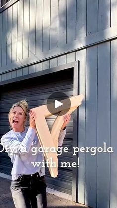 a woman is holding up a cardboard v sign in front of a garage door that says,