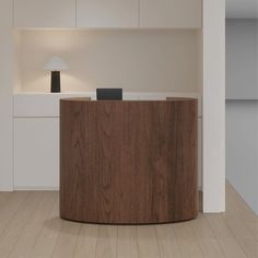 an office desk with a lamp on it in front of a white wall and wooden floor