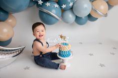 a baby boy sitting in front of a cake