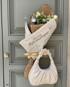 a bouquet of flowers sitting on top of a door handle next to a newspaper bag