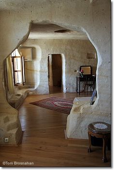 an arched doorway leads into a living room with wood floors and stone walls, along with a rug on the floor