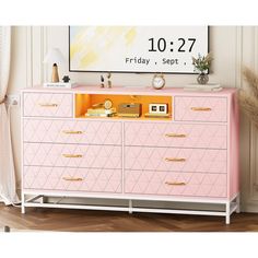 a pink dresser with gold handles and drawers in front of a large poster on the wall