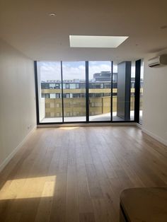 an empty room with wood flooring and large windows overlooking the cityscape outside