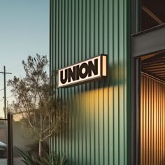 the union sign is lit up in front of a green building with metal sidings