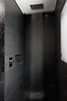 a shower head in a black tiled bathroom