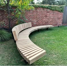 a curved wooden bench sitting in the grass