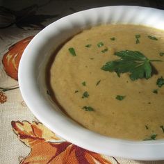 a white bowl filled with soup and garnished with parsley on the side