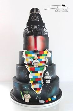 a star wars themed cake with legos on the top and bottom tier, including darth vader's helmet