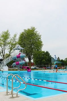 an empty swimming pool with a slide in the background