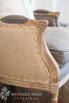 a close up of a chair on a wooden floor with pillows in the back ground