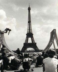 black and white photograph of people sitting on skateboards in front of the eiffel tower