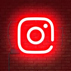 the instagram logo is lit up on a brick wall in front of a red light