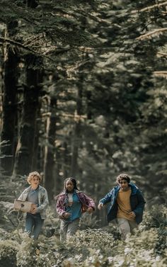 three people are walking through the woods together