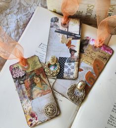 three bookmarks with different designs on them sitting next to an open book and ribbon