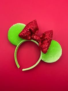 a minnie mouse headband with red sequins and a green bow on top