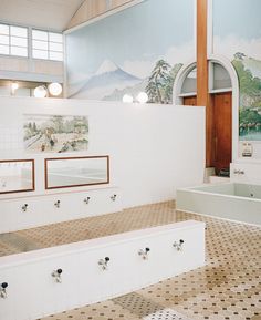 a large bathroom with tiled floors and wall paintings on the walls, along with bathtubs