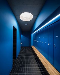 an empty hallway with blue lockers and black tile flooring on either side of the room