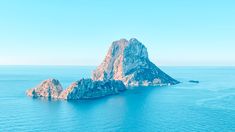 an island in the middle of the ocean with blue water and rocks on each side