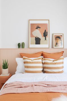 an orange and white bed with two pictures on the wall