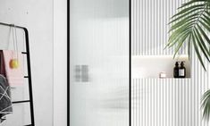 a bathroom with a towel rack and mirror next to a potted plant on the wall