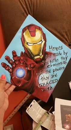 a person holding up a book with an iron man painting on it