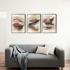 two paintings hang on the wall above a couch