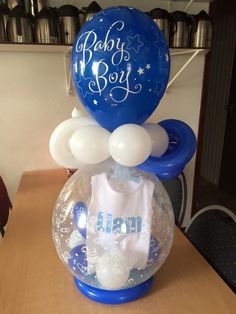 a baby boy balloon in a bubble ball on a table with other balloons and decorations