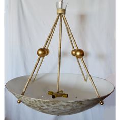 a white bowl with two gold balls on it and a candle holder in the middle