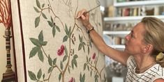 a woman is painting a wall with flowers on it