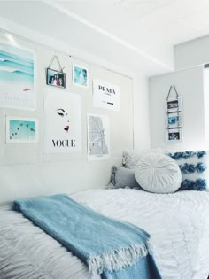 a bedroom with white walls and pictures on the wall above the bed, along with blue throw pillows