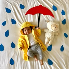 a small child laying on a bed with an umbrella and stuffed animal next to it