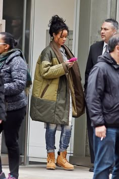 a woman standing in front of a building while looking at her cell phone