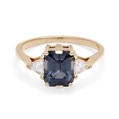 A three stone engagement ring with an emerald cut and emerald shape grey spinel center stone with two white diamond trillion side stones set in yellow gold. Nyc Engagement Rings, Anna Sheffield, Trillion Diamonds, Spinel Ring, Three Stone Ring, Pink Morganite, Grey Diamond, Champagne Diamond, Three Stone Rings