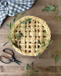 an overhead view of a pie on a table with scissors and greenery next to it